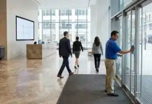 A professional day porter wiping down a high-touch surface in a modern office lobby during business hours to ensure a clean facility environment.